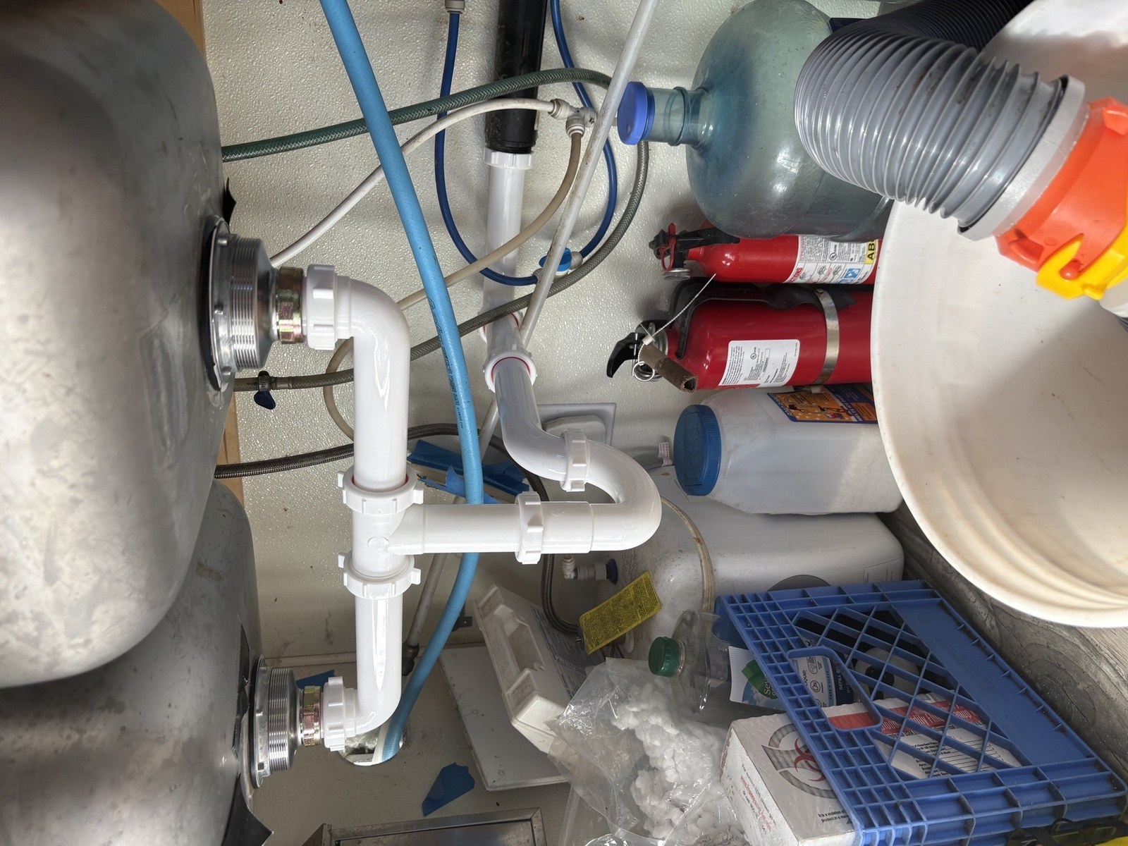 Commercial prep sink underside with new chrome basket strainers and correctly assembled white tubular waste piping