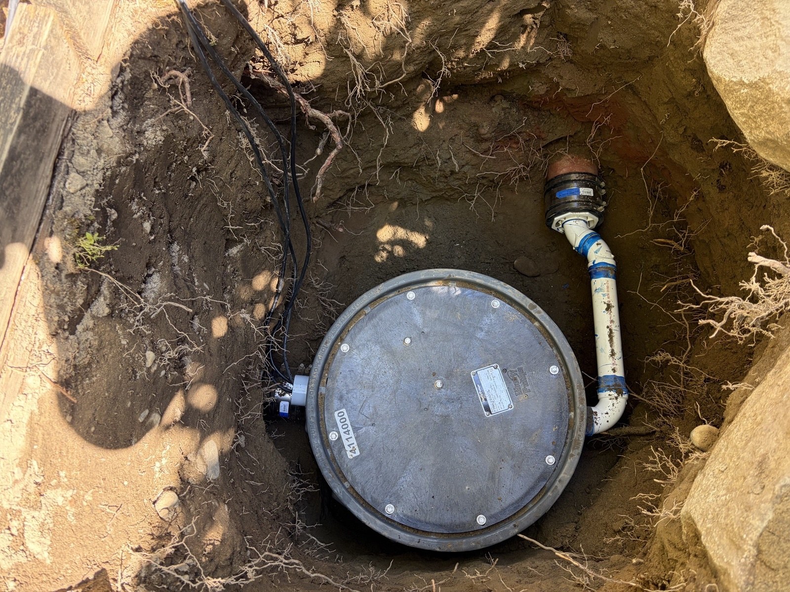 New sewage ejector basin in an excavation with discharge piping, check valve and a coupling into old clay pipe